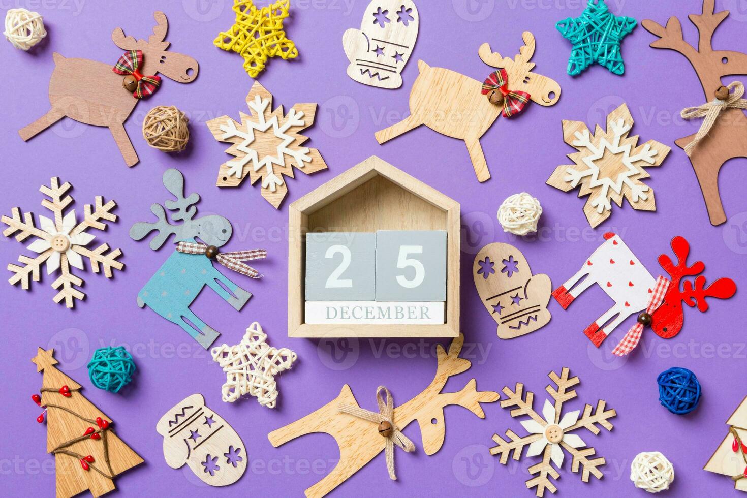 Festive decorations and toys on purple background. Top view of wooden calendar. The twenty fifth of December. Merry Christmas concept photo