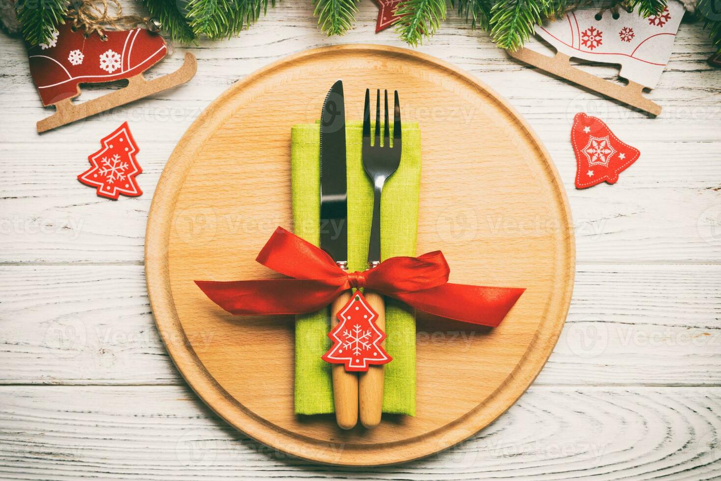 Top view of cutlery and plate on festive wooden background. New Year family dinner concept. Fir tree and Christmas decorations photo