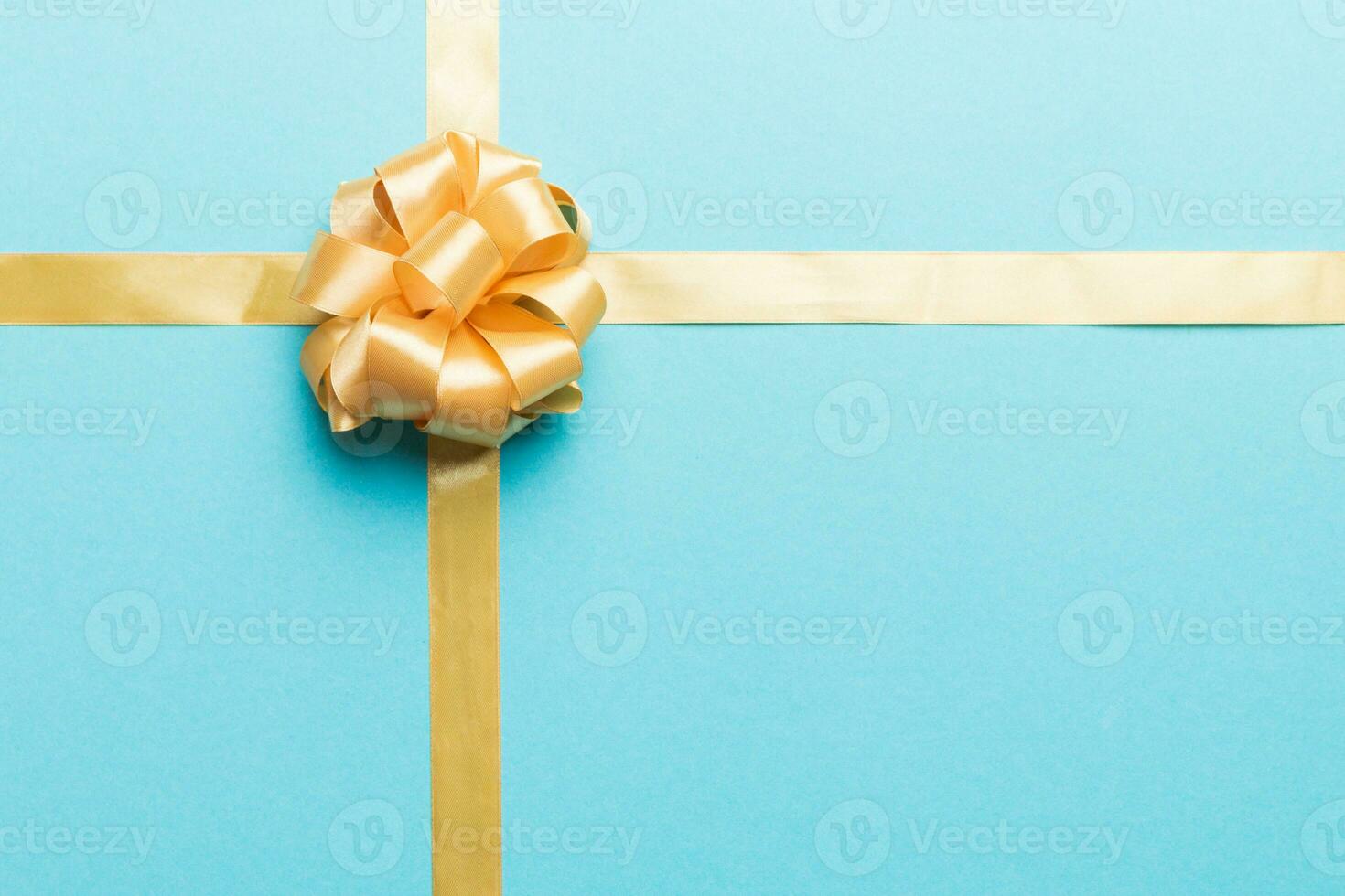 Top view of gold ribbon rolled and yellowbow isolated on colored background. Flat lay with copy space photo