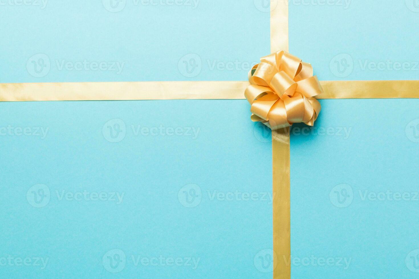 Top view of gold ribbon rolled and yellowbow isolated on colored background. Flat lay with copy space photo