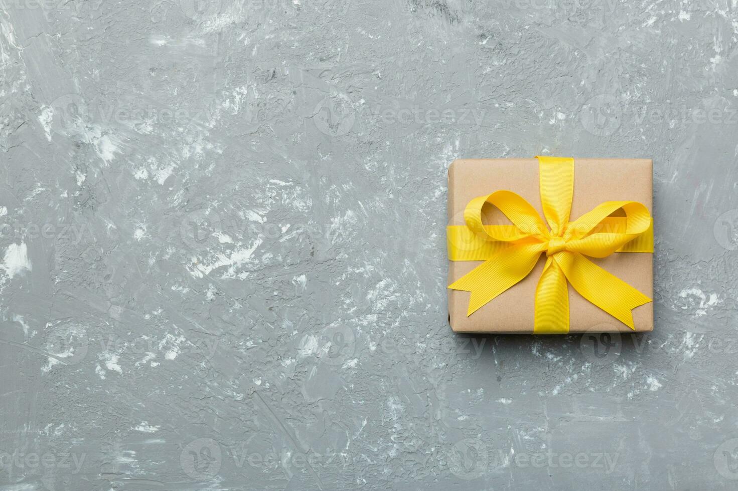 Holiday gift box wrapped in craft paper with colored bow on table background. Top view, flat lay, copy space photo
