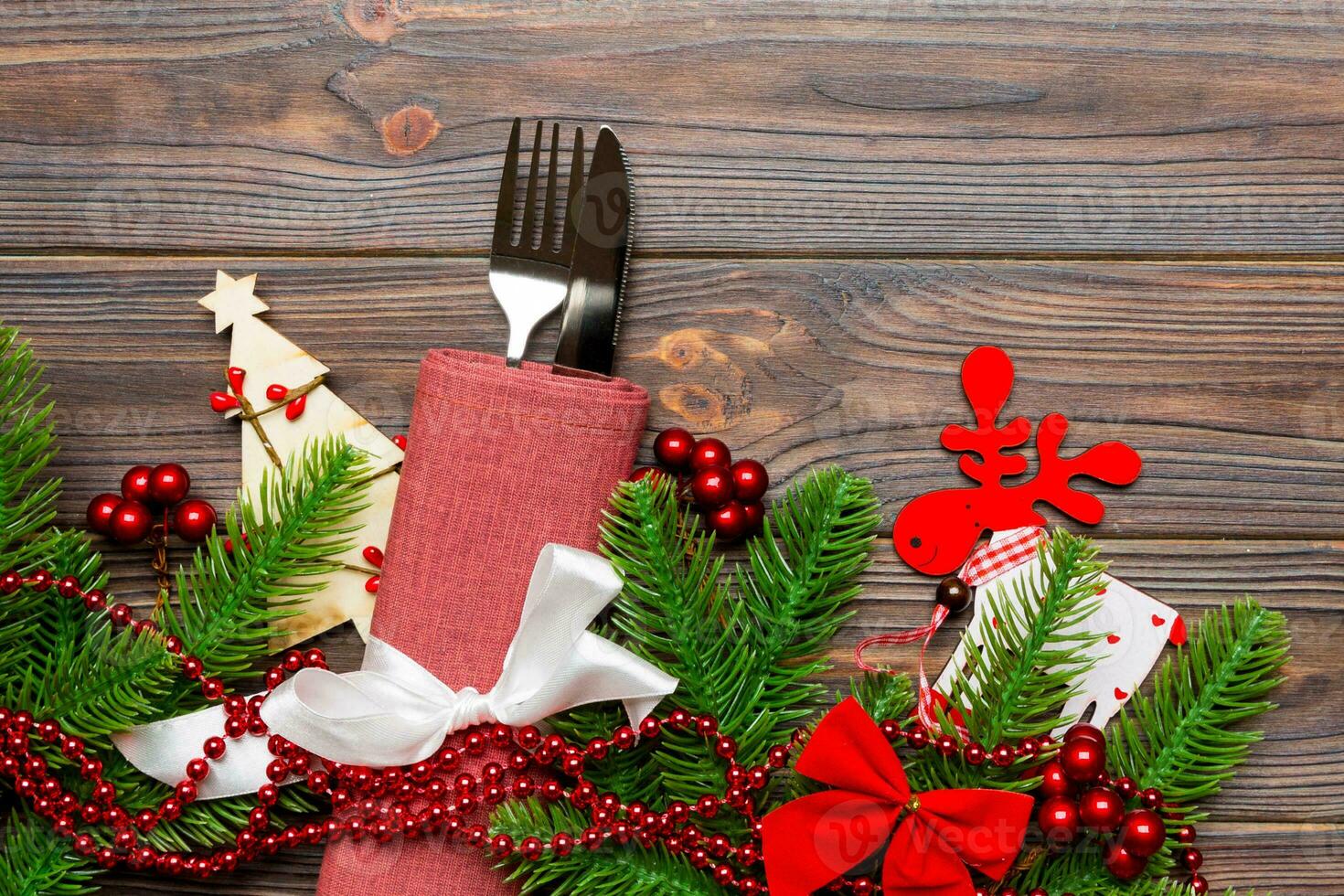 Top view of flatware tied up with ribbon on napkin on wooden background. Christmas decorations and reindeer with empty space for your design. New Year holiday concept photo