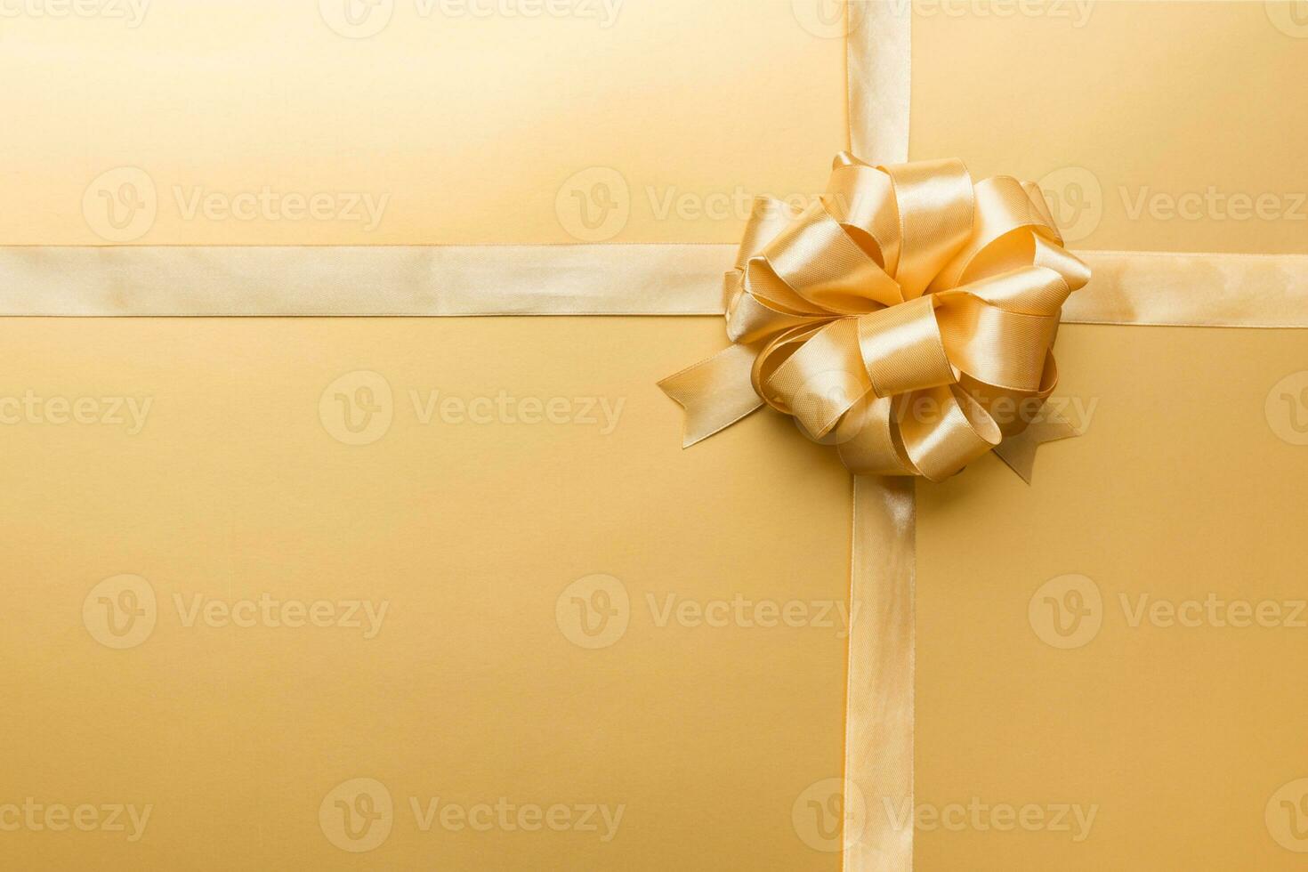 Top view of gold ribbon rolled and yellowbow isolated on colored background. Flat lay with copy space photo