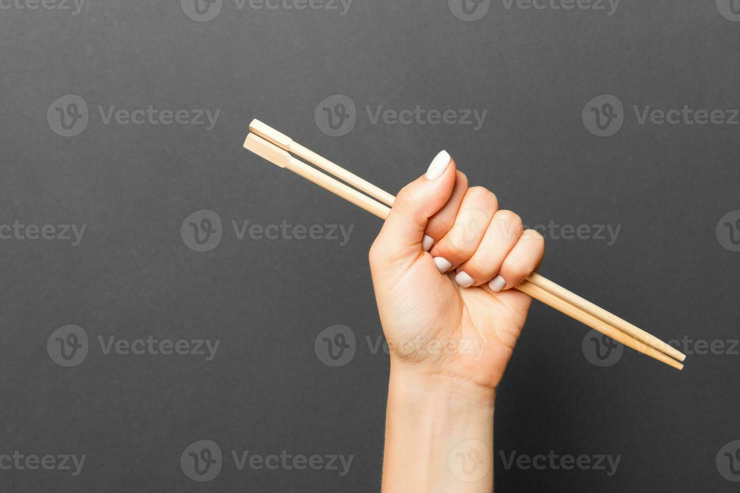 Woman's hand holding chopsticks on black background. Chinese food concept with empty space for your design photo