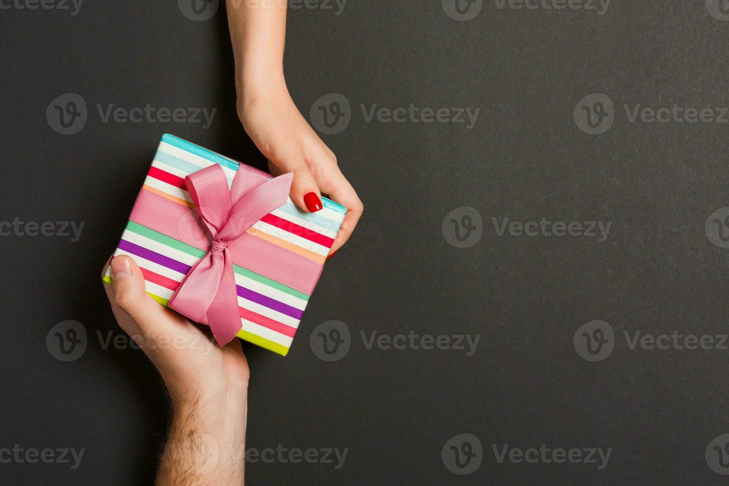 Top view of a man and a woman holding a gift box on colorful background. Love and relationship concept. Copy space photo