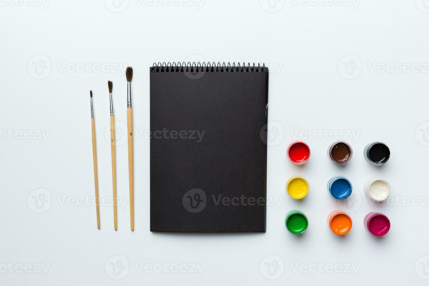 Album pages and paints, pencils, brush on a colored background. Top view with empty space. workplace for creativity. home teaching concept drawing photo