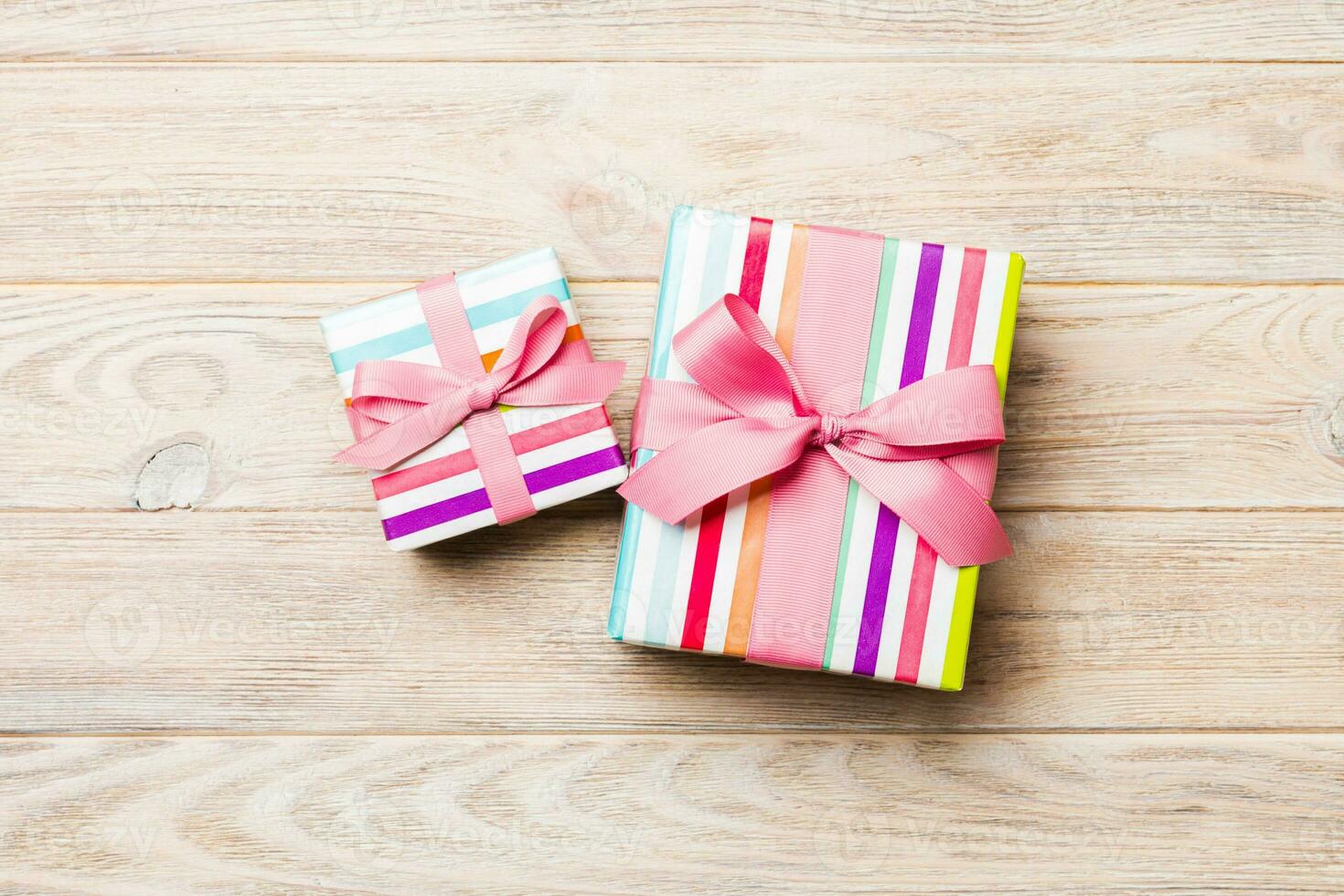 Beautiful gift box with a colored bow on the orange wooden table. Top view with copy space for you design. Christmas concept photo