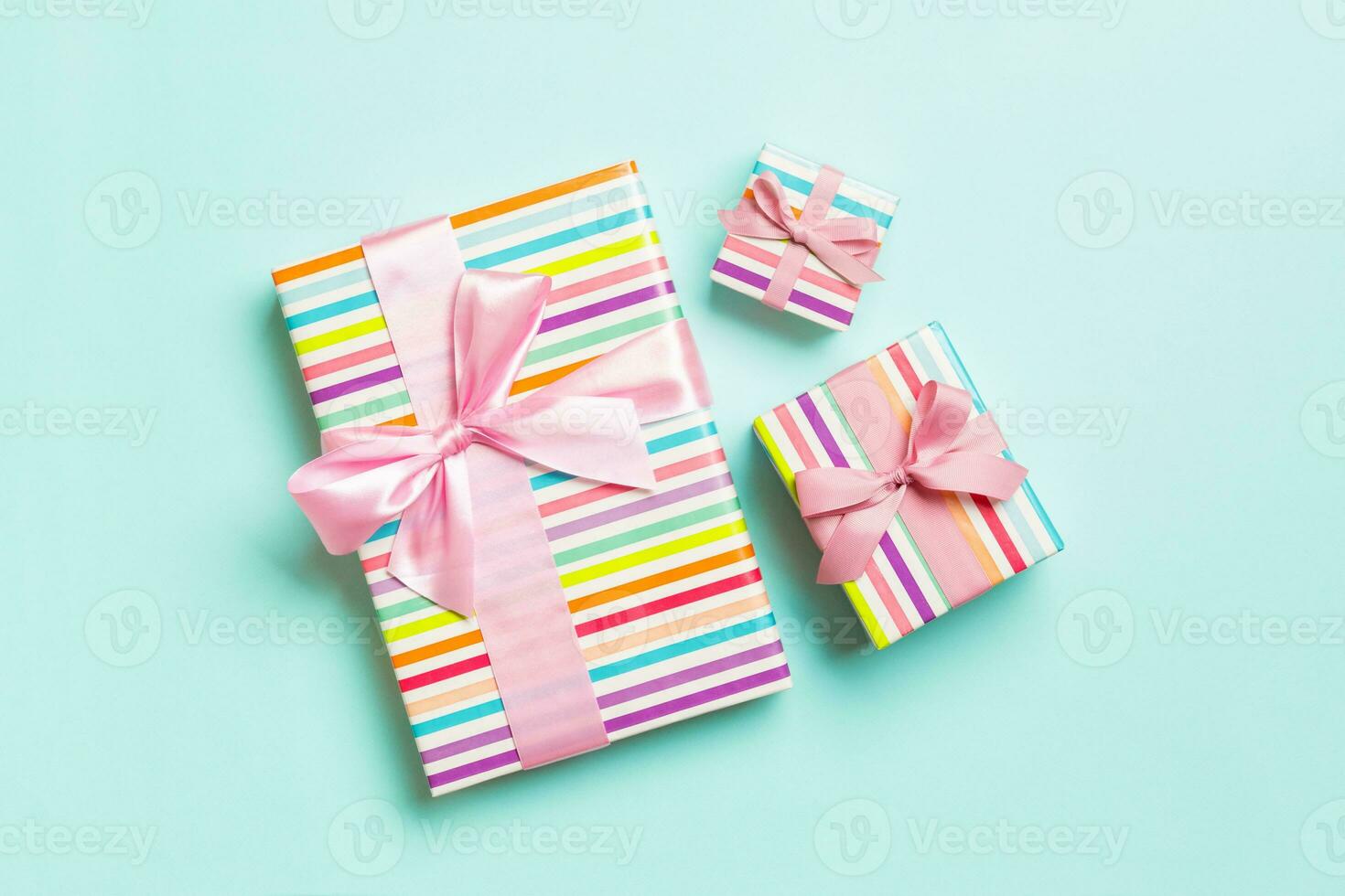 wrapped Christmas or other holiday handmade present in paper with pink ribbon on blue background. Present box, decoration of gift on colored table, top view photo