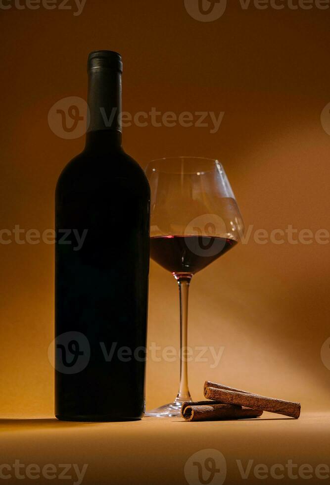 botella con rojo vino y vaso y canela foto