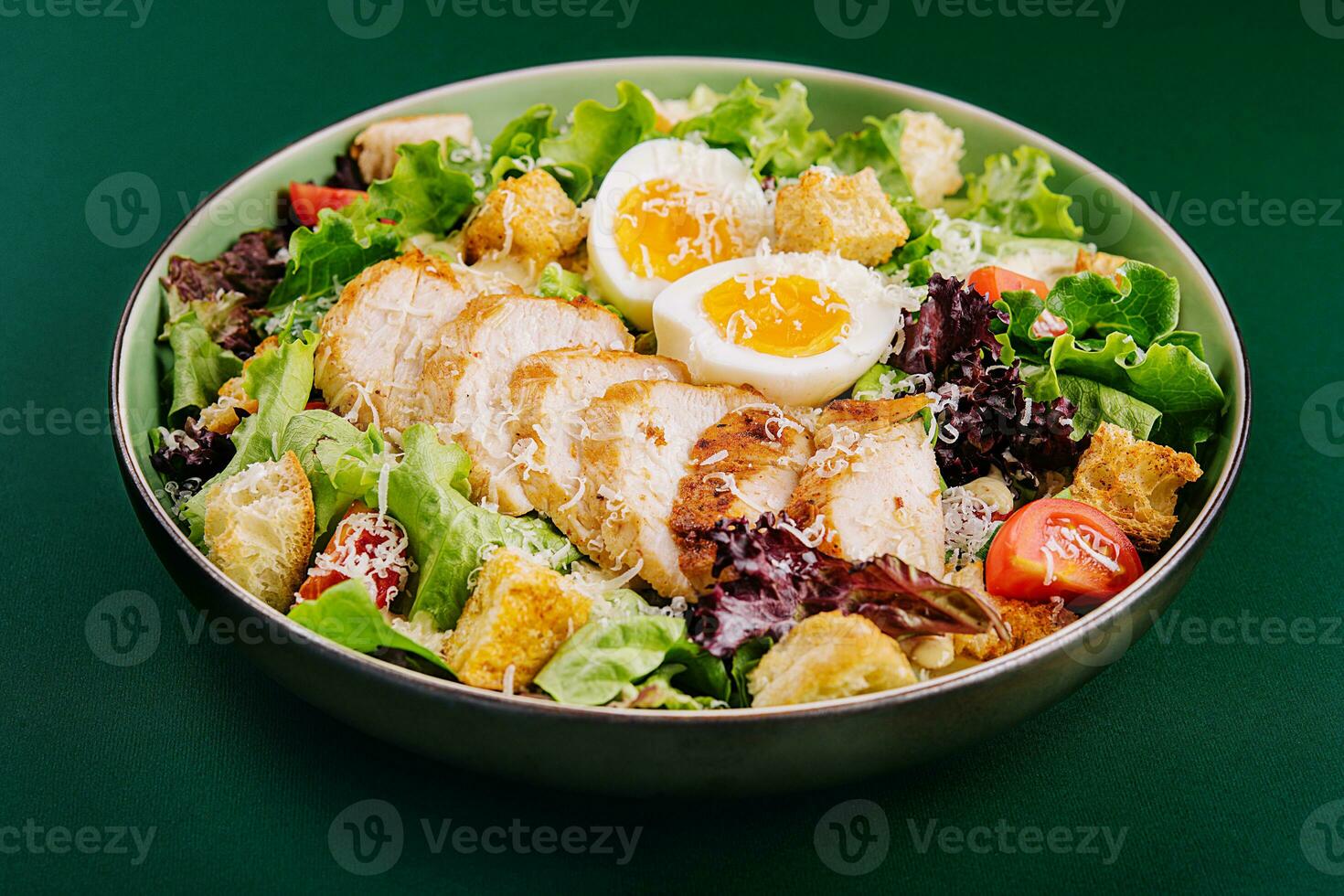 Caesar salad with chicken breast on green background photo