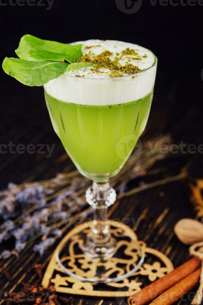 Fresh basil sour cocktail with white foam with green basil leaf in a glass photo