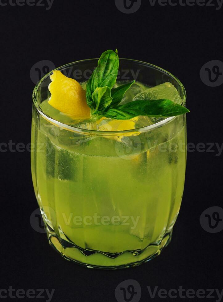 Fresh summer green basil cocktail in a glass on dark background photo