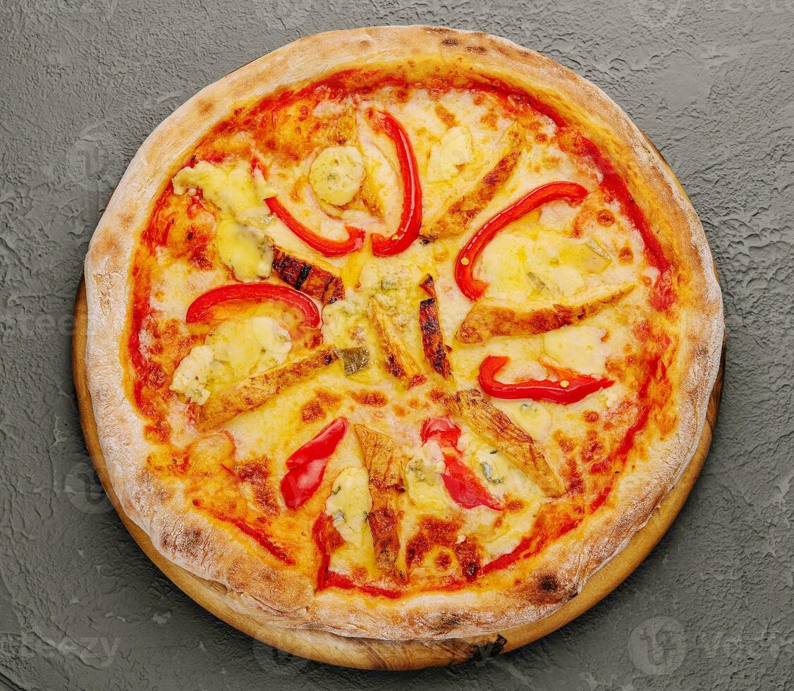A top view of cheesy chicken pizza with sliced red bell pepper photo