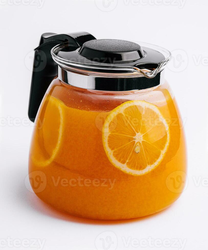 Orange tea in a jug with orange pieces photo