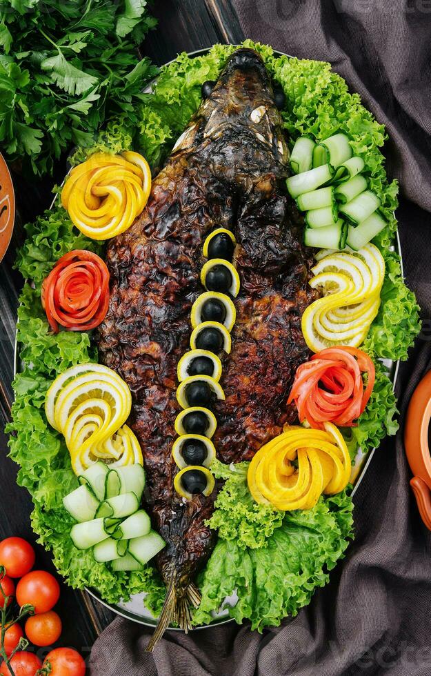 baked carp with vegetables close-up in a baking dish on the table photo