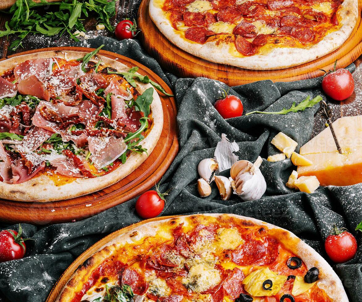 Tasty assorted three pizzas on a wooden boards photo