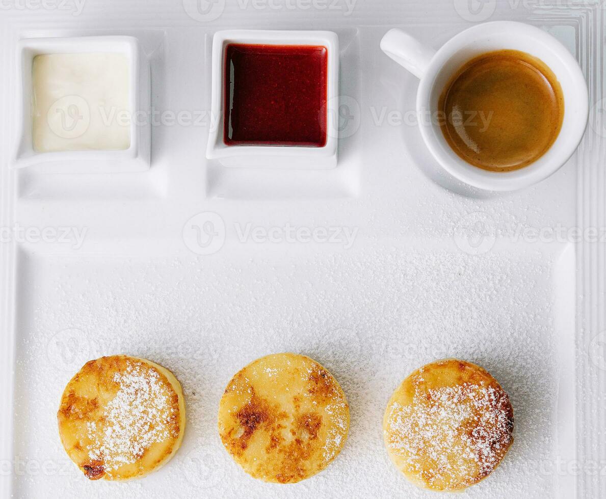 Cottage cheese pancakes with berry sauce and sour cream and coffee photo