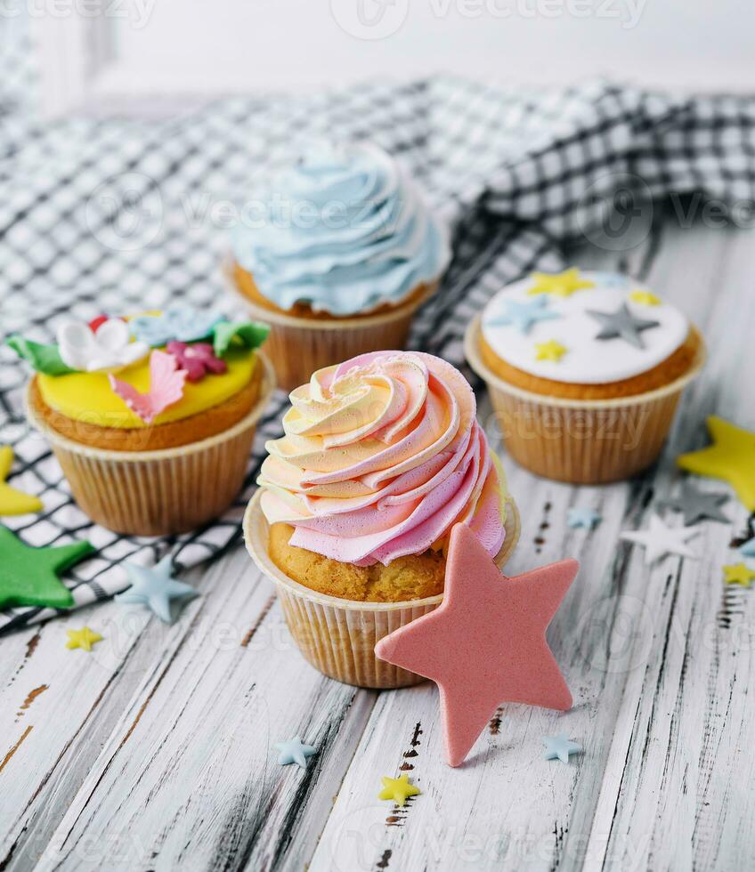 Multiple colorful nicely decorated muffins on a wooden background photo