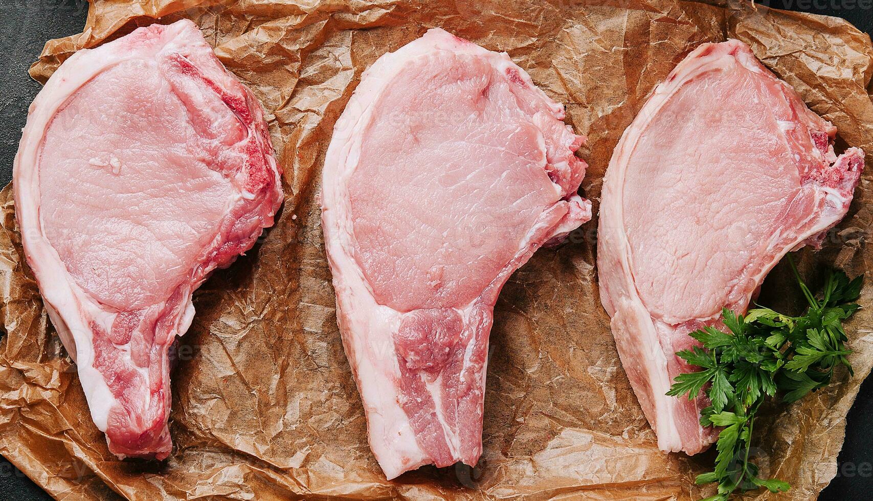 Several raw pork steaks on baking paper photo
