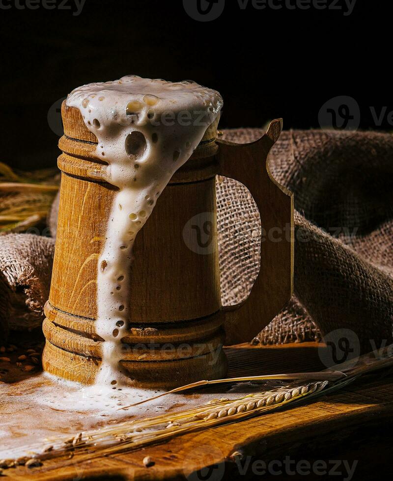 Wooden beer mug with beer and foam standing on a wooden table photo