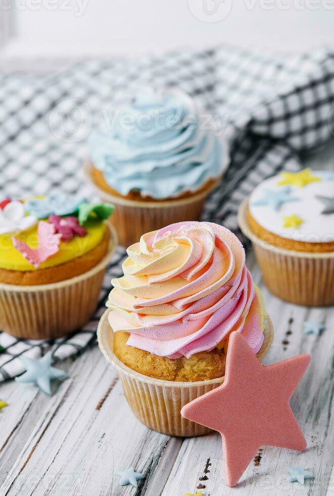 Multiple colorful nicely decorated muffins on a wooden background photo