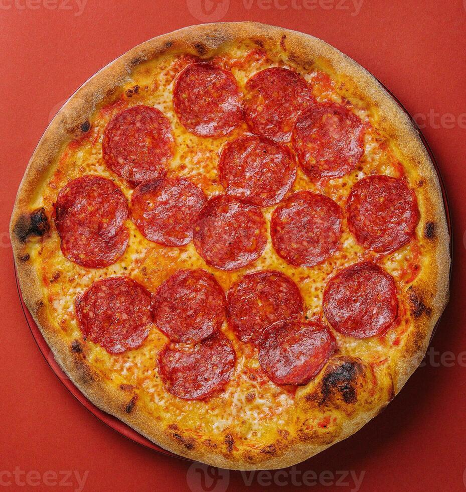 Fresh tasty pizza with pepperoni on red background photo