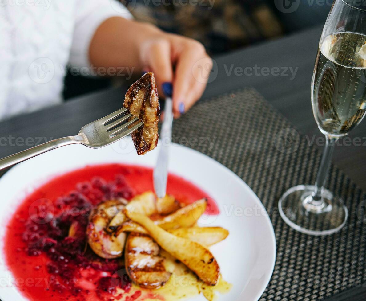 mujer comiendo carne y bebida champán en un restaurante foto