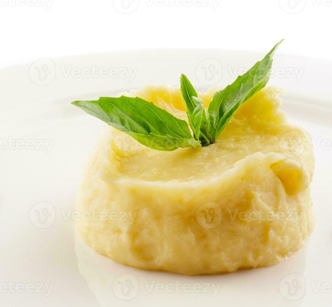 Mashed potatoes and basil on white plate photo