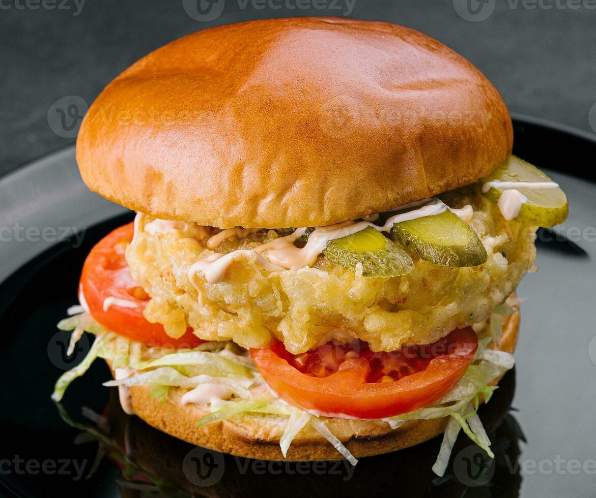 Fried fish fillet burger on black plate photo