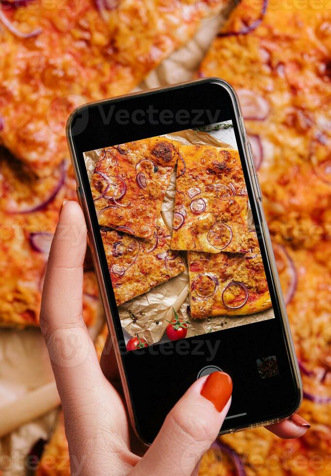Female hand making a photo of pizza with a mobile phone