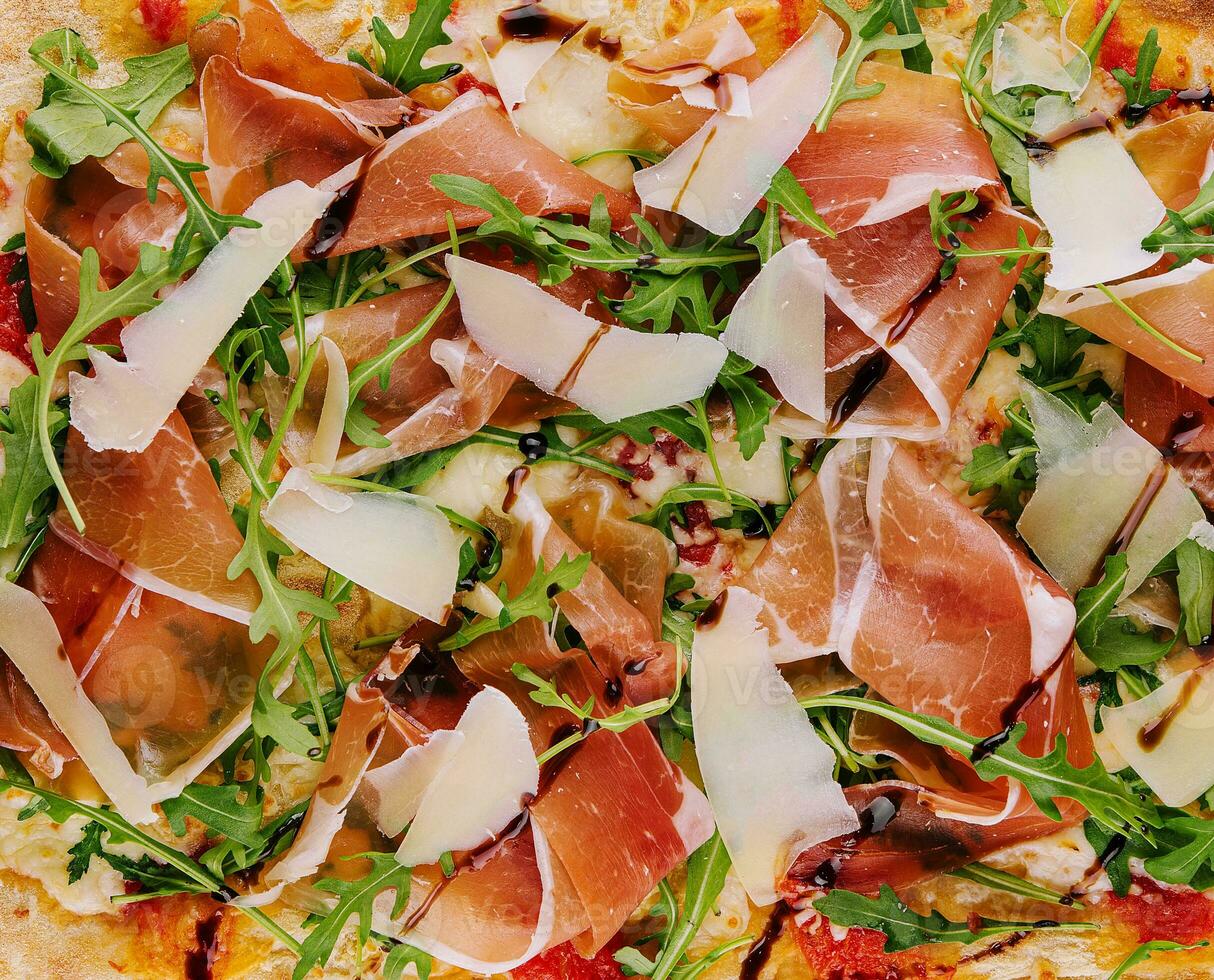 Fresh pizza Parma made of parmesan, prosciutto ham and arugula photo