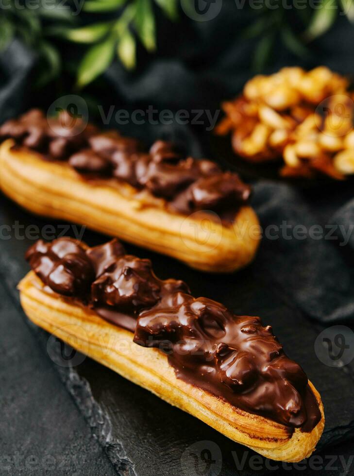 Two eclairs with dark chocolate on black board photo