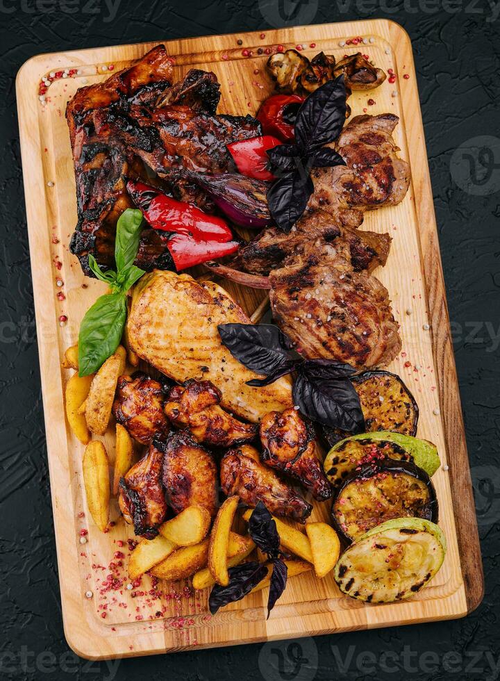 Mixed meat dish. grilled ribs, chicken wings, rack of lamb with vegetables photo