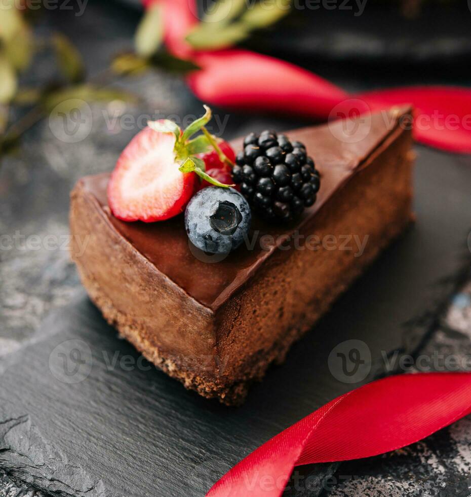 Delicious chocolate cake decorated with fresh berries on stone table photo