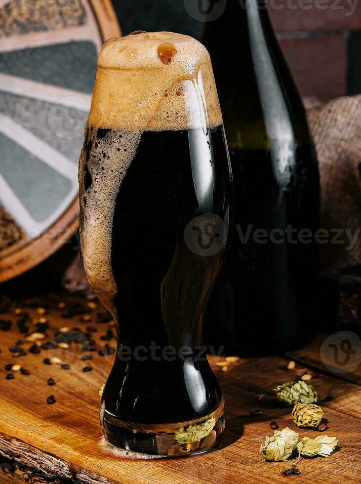 Glass of dark beer and bottle on wooden photo