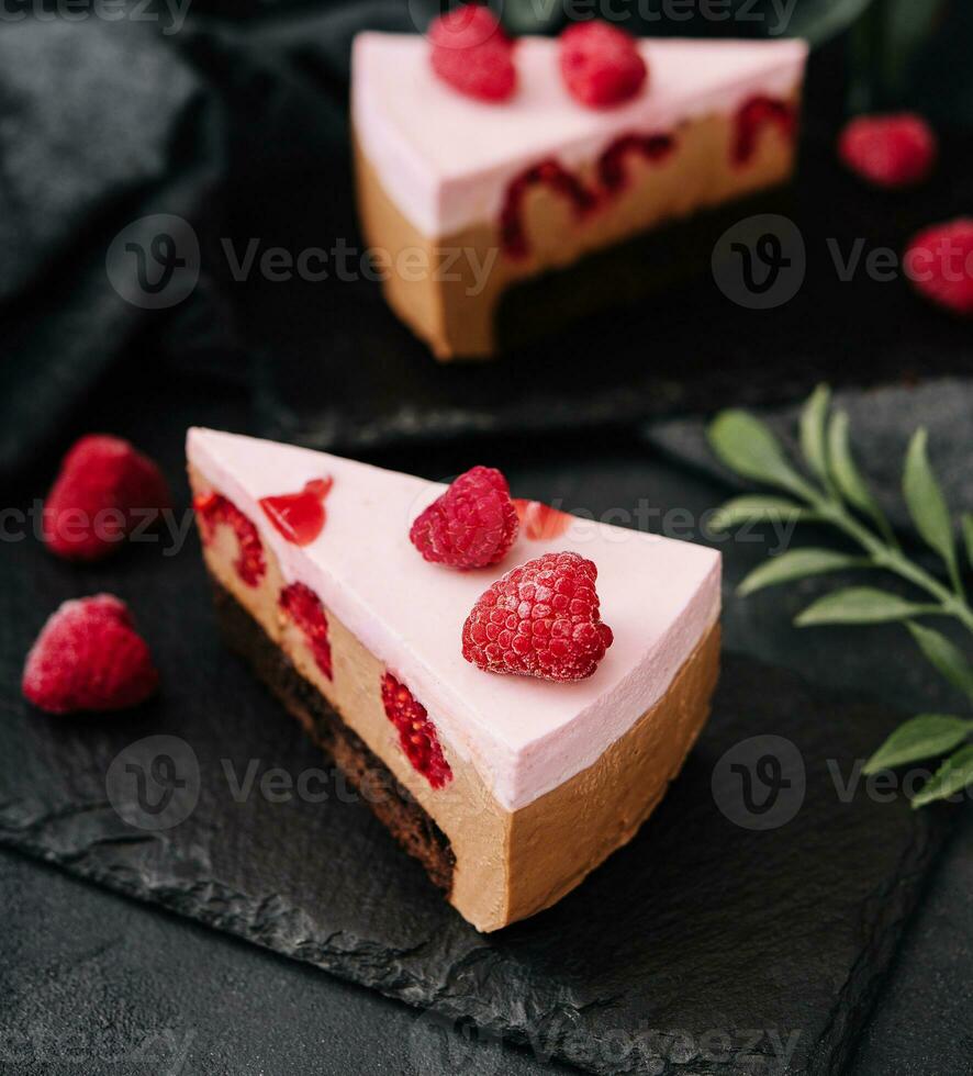 Pieces of cheesecake with raspberries on black board photo