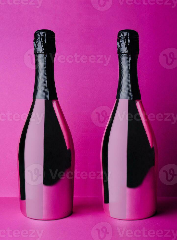 two champagne bottles on pink background photo
