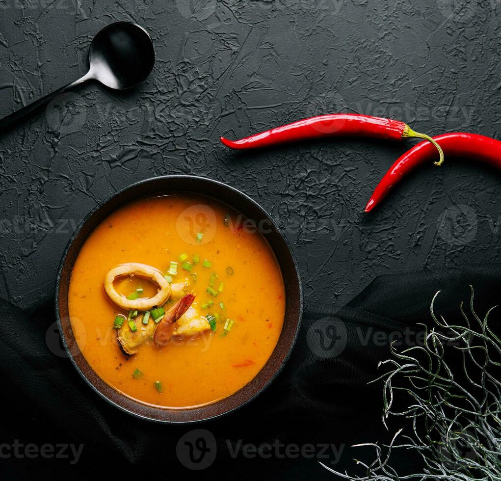Tom yam seafood soup from above on black stone photo