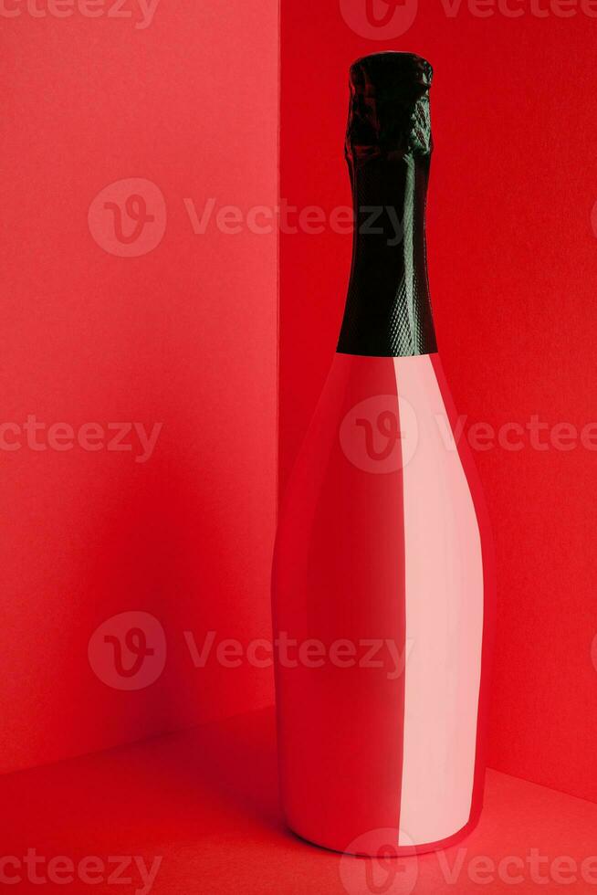 Red bottle of champagne on red background photo