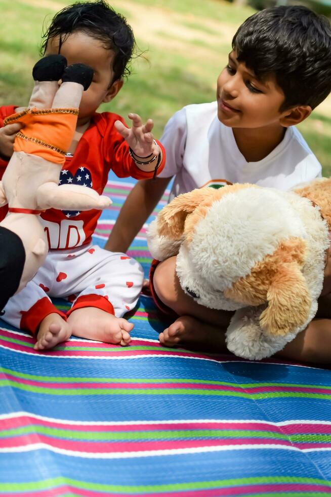 dos contento Niños en sociedad parque, contento asiático hermanos quien son sonriente felizmente juntos. hermanos jugar al aire libre en verano, mejor amigos. niñito bebé chico jugando con su contento hermano en el jardín foto