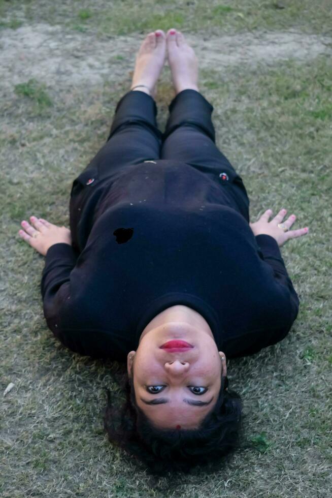 joven india practicando yoga al aire libre en un parque. hermosa chica practica pose básica de yoga. calma y relax, felicidad femenina. posturas básicas de yoga al aire libre foto