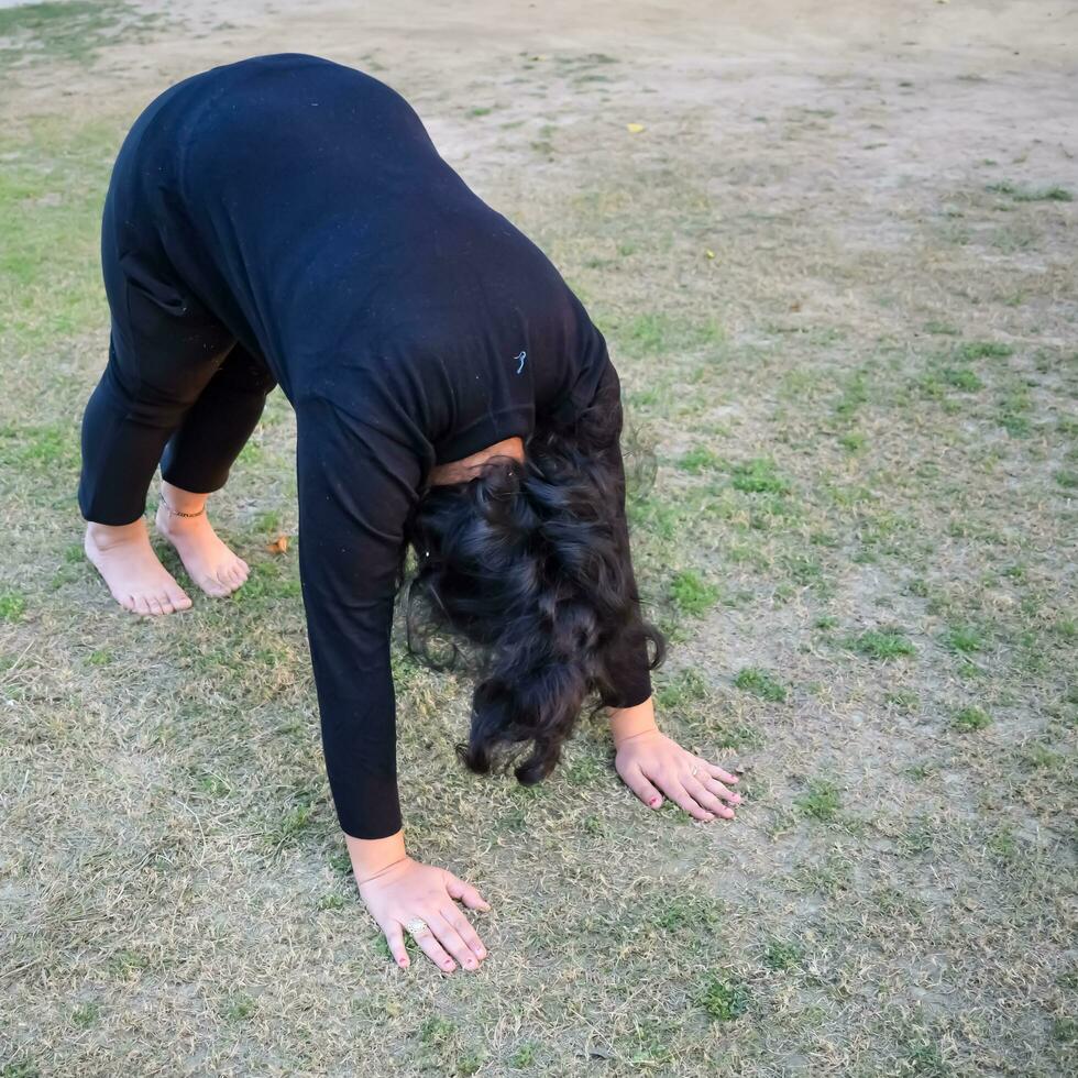 Young Indian woman practicing yoga outdoor in a park. Beautiful girl practice basic yoga pose. Calmness and relax, female happiness. Basic Yoga poses outdoor photo