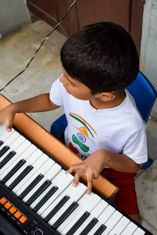 Asian boy playing the synthesizer or piano. Cute little kid learning how to play piano. Child's hands on the keyboard indoor. photo