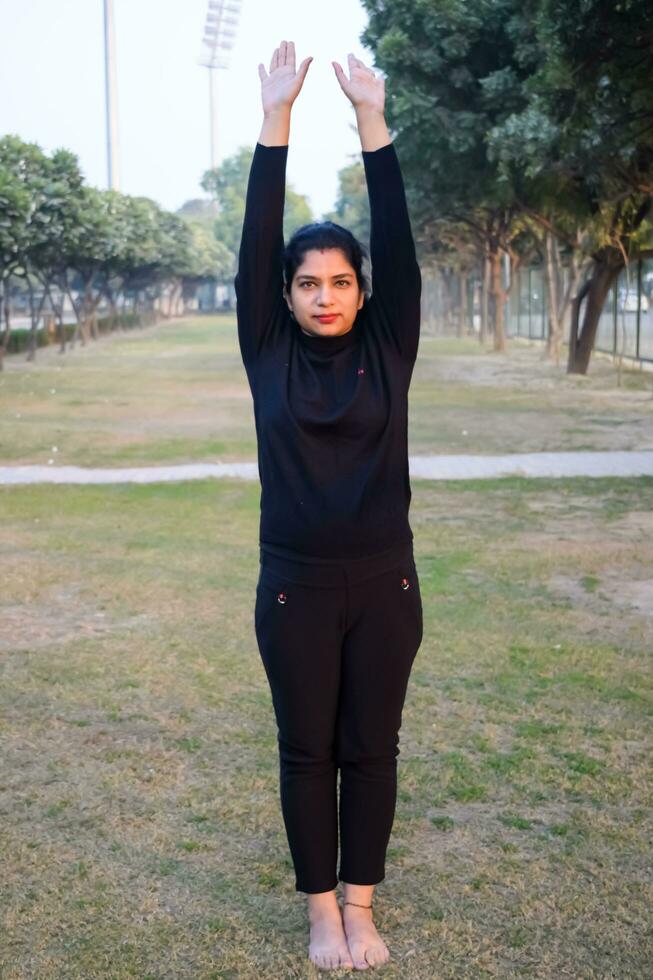 joven india practicando yoga al aire libre en un parque. hermosa chica practica pose básica de yoga. calma y relax, felicidad femenina. posturas básicas de yoga al aire libre foto