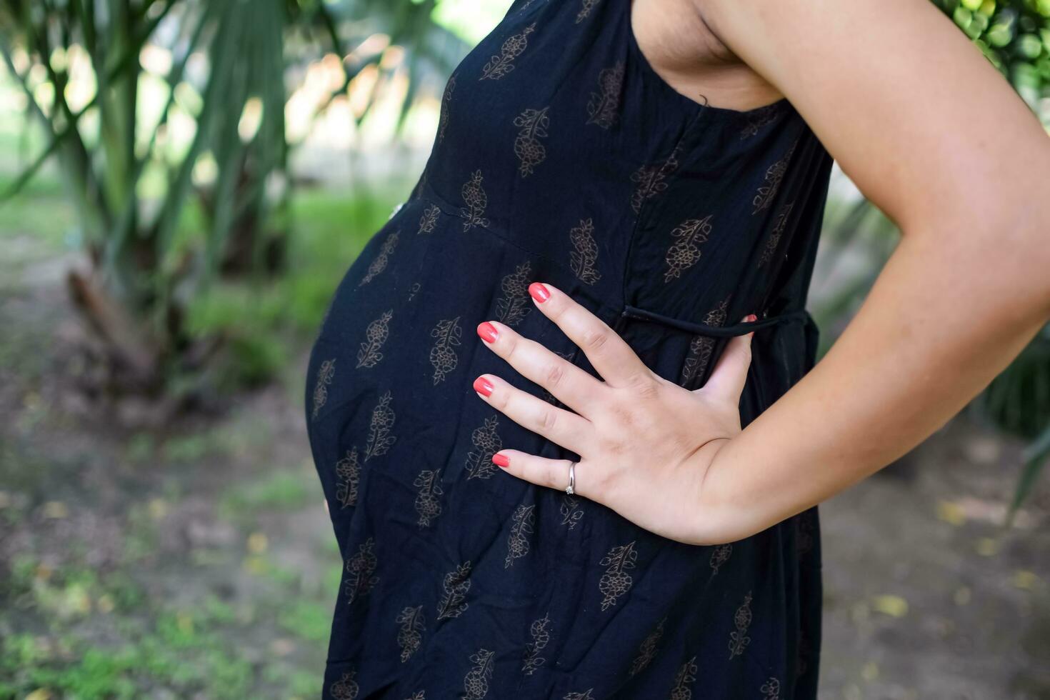 A pregnant Indian lady poses for outdoor pregnancy shoot and hands on  belly, Indian pregnant woman