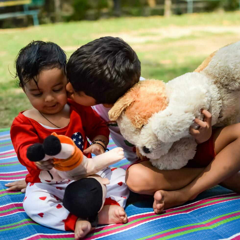 dos contento Niños en sociedad parque, contento asiático hermanos quien son sonriente felizmente juntos. hermanos jugar al aire libre en verano, mejor amigos. niñito bebé chico jugando con su contento hermano en el jardín foto