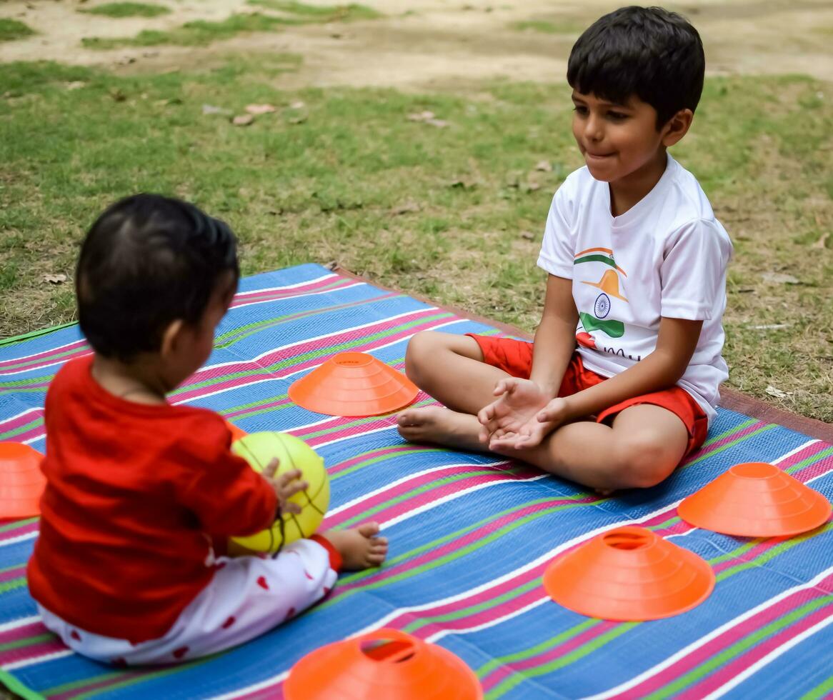 dos contento Niños en sociedad parque, contento asiático hermanos quien son sonriente felizmente juntos. hermanos jugar al aire libre en verano, mejor amigos. niñito bebé chico jugando con su contento hermano en el jardín foto