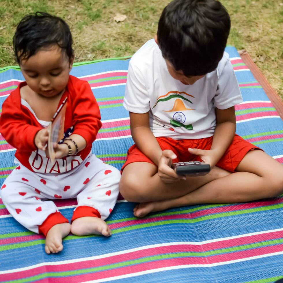 Two happy boys in society park, happy Asian brothers who are smiling happily together. Brothers play outdoors in summer, best friends. Toddler baby boy playing with his happy brother in the garden photo