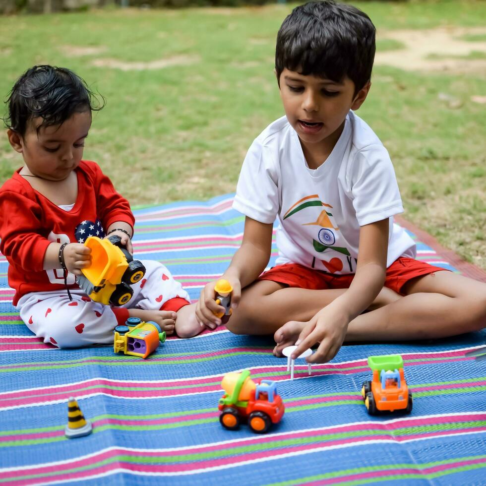 Two happy boys in society park, happy Asian brothers who are smiling happily together. Brothers play outdoors in summer, best friends. Toddler baby boy playing with his happy brother in the garden photo