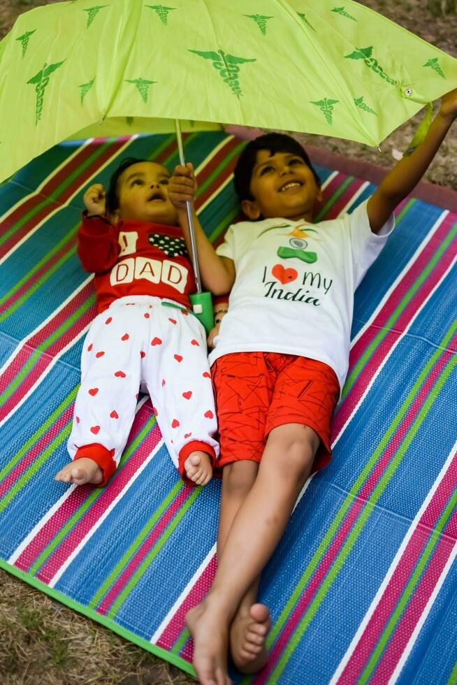 Two happy boys in society park, happy Asian brothers who are smiling happily together. Brothers play outdoors in summer, best friends. Toddler baby boy playing with his happy brother in the garden photo